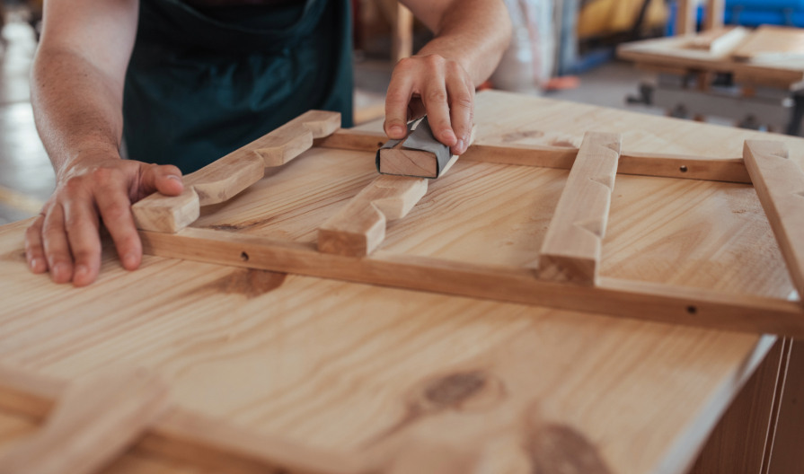 person sanding wood with a sand paper wrapped in a wood block